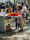 Girl with elements of clothing and make-up of an anime character standing at a kiosk with food among other visitors to the park