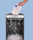 Absentee ballot of vote by mail envelope being shredded in an office shredder