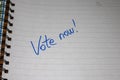 Vote now, handwriting  text on paper, political message. Political text on office agenda. Concept of democracy, voting, politics. Royalty Free Stock Photo