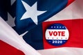 Vote presidential election campaign 2020 vote button; pin laying on the american flag.