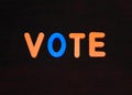 Vote word written with different colored letter blocks on a dark background