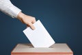 Voter Holds Envelope In Hand Above Vote Ballot. Blue background. Democracy Concept