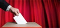 Voter Holds Envelope In Hand Above Vote Ballot On Red Background. Freedom Democracy Concept Royalty Free Stock Photo