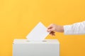 Voting woman near ballot box on color background