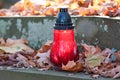 Votive candle at the grave with autumn leaves