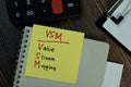 VSM - Value Stream Mapping write on sticky notes isolated on Wooden Table Royalty Free Stock Photo