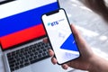 VTB mobile banking app in Russia. Hand with smartphone, logo on the screen. Background with national flag