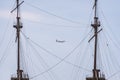 A Vueling airlines aircraft over Genoa between two masts of the ship.