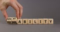 Vulnerability or adaptability symbol. Businessman turns wooden cubes and changes words `vulnerability` to `adaptability`. Grey