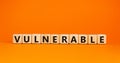 Vulnerable symbol. The word Vulnerable on wooden cubes. Beautiful orange table, orange background. Business and vulnerable concept Royalty Free Stock Photo