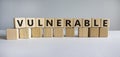 Vulnerable symbol. The word Vulnerable on wooden cubes. Beautiful white table, white background. Business and vulnerable concept.