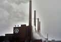 VW combined heat and power plant with smoking and steaming chimneys and the Volkswagen emblem on the brick wall in Wolfsburg,