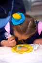 Vyshyvanka day in Ukraine. Kid painting Ukrainian flag in shape of heart on gingerbread