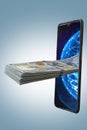 A wad of American 100 dollar bills protrude from a mobile phone. Concept: earning money through mobile apps and the Internet, Royalty Free Stock Photo