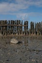 The wadden sea at paesens moddergat, wooden poles, big rock in foreground, sea and sky