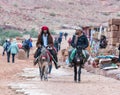 Two Bedouins ride donkeys and talk to each other in Petra near Wadi Musa city in Jordan