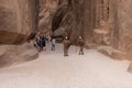 Two Bedouins dressed in uniform of Nabatean warriors stand for tourists in front of the entrance to the gorge Al Siq in Petra in