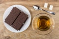 Wafer in chocolate, tea on saucer, sugar, teaspoon on table