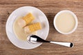 Wafer rolls with condensed milk, spoon in saucer, bowl with condensed milk on table. Top view Royalty Free Stock Photo