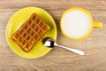 Wafer stuffed in yellow saucer, cup of milk and spoon Royalty Free Stock Photo