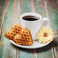 Waffle biscuits in shape of heart with cup of coffee and flower on vintage background Royalty Free Stock Photo