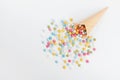 Waffle cone and heap colorful candy on white background from above. Flat lay style.