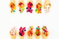 Waffle cones with assorted bright candy on white background. Flat lay, top view