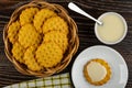 Cookies in wicker basket, spoon in bowl with condensed milk, cookie poured condensed milk in saucer, napkin on wooden table. Top Royalty Free Stock Photo