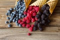 Waffle with fresh berries. Berries. Raspberries, blackberries, blueberries in waffle cones on a gray abstract background.