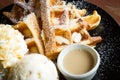 Waffle with ice-cream on black plate.