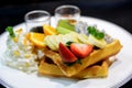 Waffle with mix fruit and whipping cream on a white plate