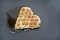 Waffle shaped like a heart, with syrup on a black plate Royalty Free Stock Photo