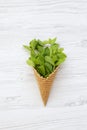 Waffle sweet cone with mint leaves over white wooden surface, view from above. Flat lay, overhead. Top view. Royalty Free Stock Photo