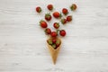 Waffle sweet ice cream cone with strawberries over white wooden background, top view. Flat lay, from above Royalty Free Stock Photo