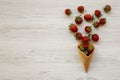 Waffle sweet ice cream cone with strawberries over white wooden surface, overhead view. Flat lay, from above Royalty Free Stock Photo