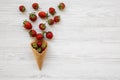 Waffle sweet ice cream cone with strawberries on a white wooden background, overhead view. Flat lay, from above. Royalty Free Stock Photo