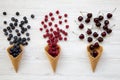 Waffle sweet ice cream cones with raspberries, cherries and blueberries over white wooden background, top view. From above, Royalty Free Stock Photo