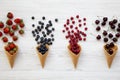 Waffle sweet ice cream cones with raspberries, cherries, strawberries and blueberries over white wooden background, overhead view Royalty Free Stock Photo