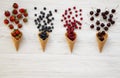 Waffle sweet ice cream cones with raspberries, cherries, strawberries and blueberries over white wooden surface, top view. Flat la Royalty Free Stock Photo