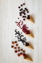 Waffle sweet ice cream cones with raspberries, cherries, strawberries and blueberries over white wooden surface, top view. Flat la Royalty Free Stock Photo