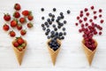 Waffle sweet ice cream cones with raspberries, strawberries and blueberries over white wooden background, top view Royalty Free Stock Photo