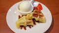 Waffle with vanilla ice cream topping and strawberry slice with chocolate sauce dessert served on white plate Royalty Free Stock Photo