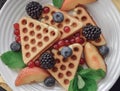 Homemade Belgian waffles served with fresh berries on white plate over wooden background, close up. Top view. Flat lay