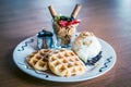 Waffles dusted with icing sugar and iceream and fruit on the side