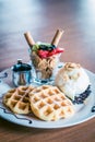 Waffles dusted with icing sugar and iceream and fruit on the side