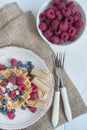 Waffles with fresh banana, raspberries, blueberries for breakfast. Fresh waffles with fruits. Light wooden background. Summer Royalty Free Stock Photo