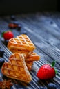 Waffles hearts with blueberry and strawberry tied with a string on the dark wooden background