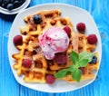 Waffles with ice cream and raspberries for breakfast over blue wooden table. Royalty Free Stock Photo