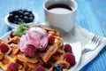 Waffles with ice cream and raspberries for breakfast over blue wooden table. Royalty Free Stock Photo