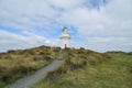 Waipapa Point Lighthouse with dunes and cloudy sky